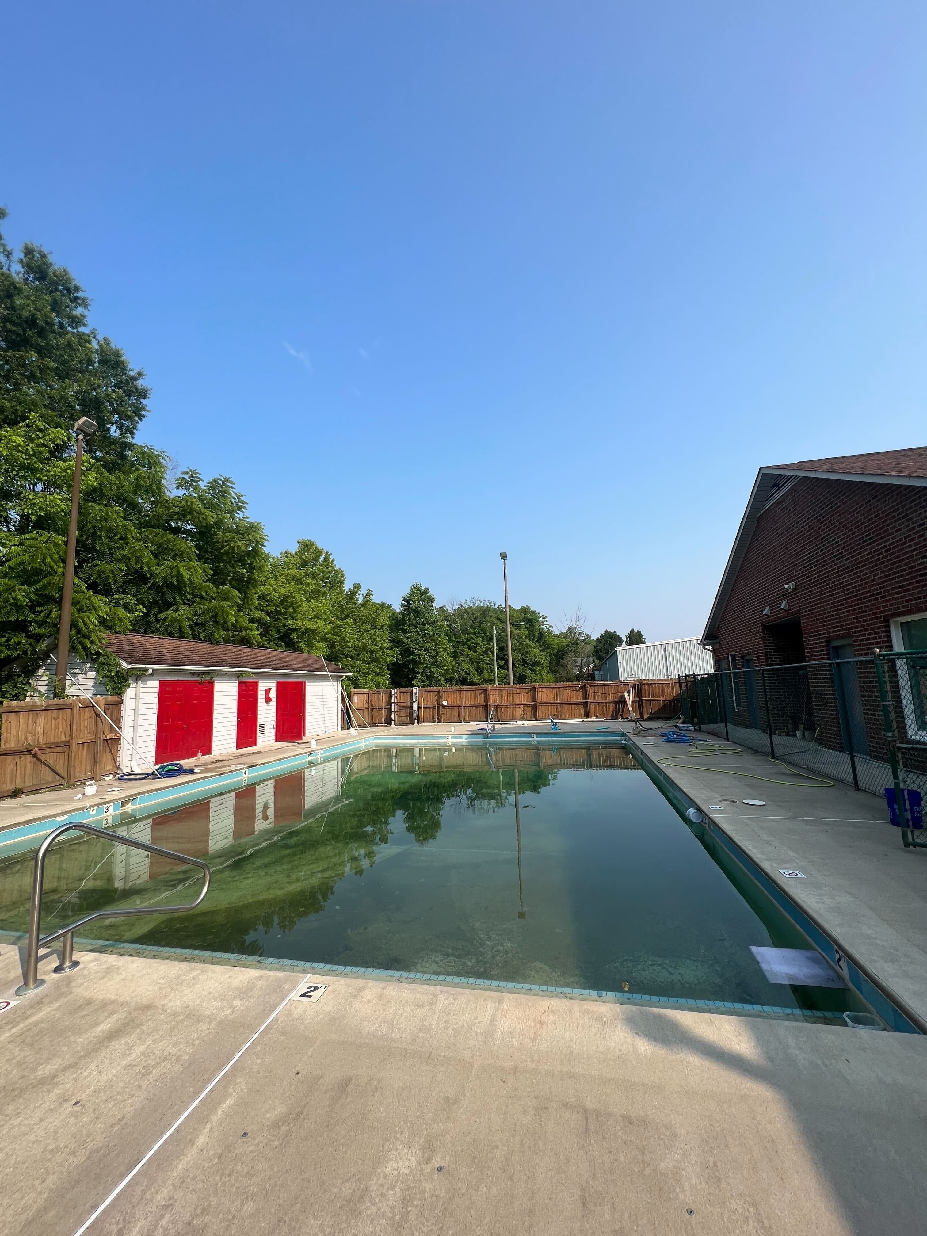 Green cloudy backyard pool water before treatment