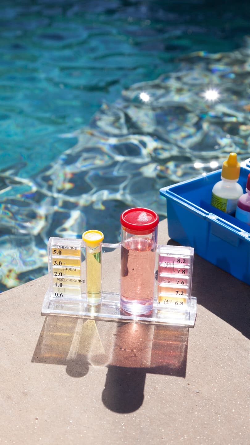 Pool water test kit showing chlorine and pH readings beside an in-ground pool