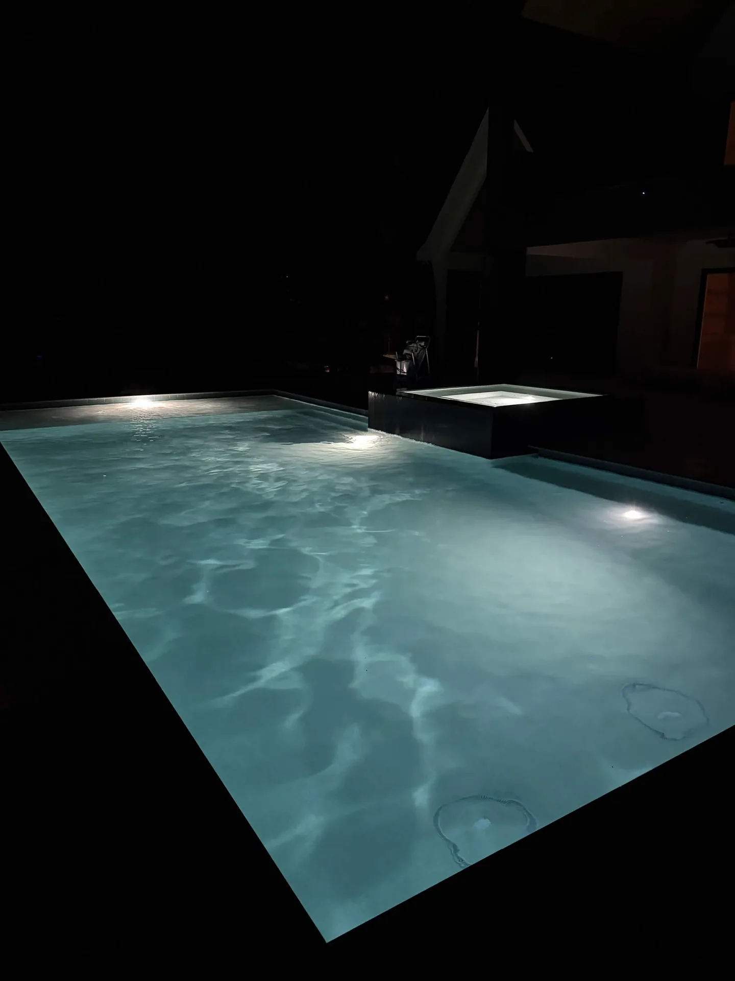 Illuminated backyard pool and spa at night
